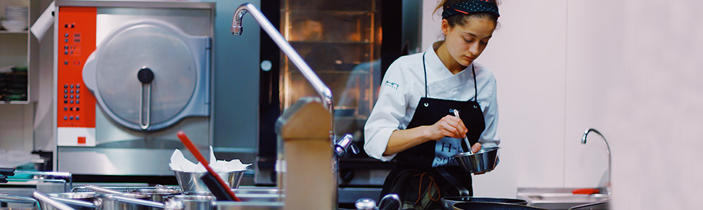 Chef mixing ingredients in a shared dark kitchen working space