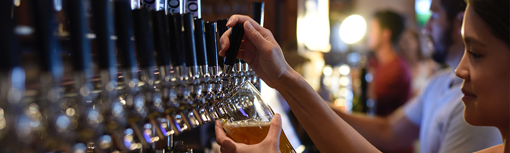 Local woman pouring her own pint in a craft brewery